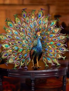 a peacock statue on top of a wooden table