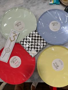 four different colored plates sitting on top of a table next to some candy bar wrappers