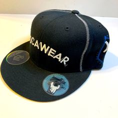 a black hat with the word rawwear on it and a blue button in front