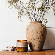 a vase sitting on top of a wooden table next to a candle