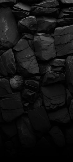 black rocks are stacked up together in this dark photo, with the light shining on them