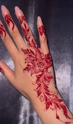 a woman's hand painted with red hennap and floral designs on it