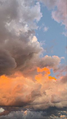 an airplane is flying in the sky with some clouds above it and another plane on the ground