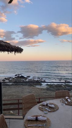 the table is set for two on the balcony overlooking the beach and ocean at sunset