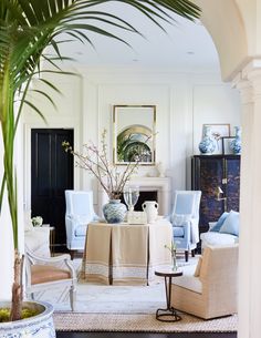 a living room filled with furniture and a potted palm tree in the middle of it