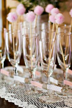 there are many wine glasses on the table with pink flowers in them and straws sticking out of them