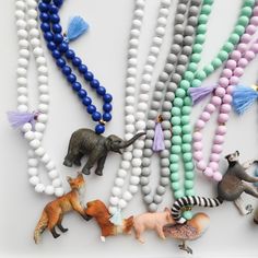 several beads with animals and tassels are arranged on a white surface, including one bead necklace