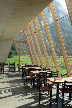 tables and chairs are lined up in front of large windows with mountains in the background