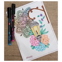 some markers and pens are sitting on a table next to a coloring book with an image of a lamp