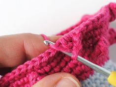 someone is crocheting the stitchs together to make a knitted bag or purse