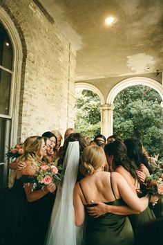 a group of women standing next to each other in front of a doorway with flowers