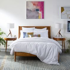 a bed with white linens and pillows in a bedroom next to two planters