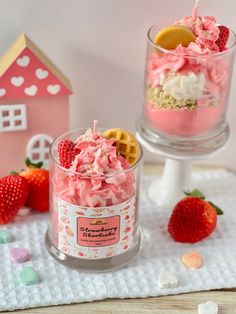 two small glass containers filled with food on top of a white cloth next to strawberries