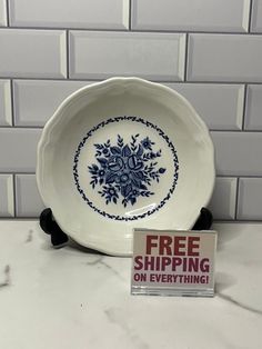 a white plate with blue flowers on it and a sign that says free shipping on everything