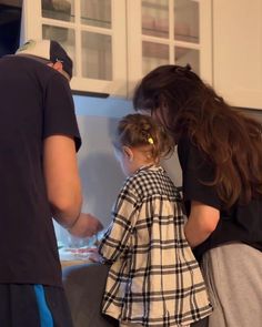 two people standing in front of a counter with food on it and one person holding a child's hand