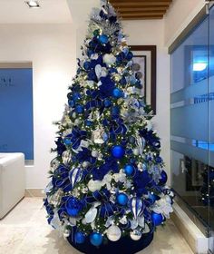 a blue christmas tree with white and silver ornaments in the corner of an office building