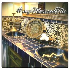 a bathroom with blue and gold tiles on the counter top, two sinks and a mirror