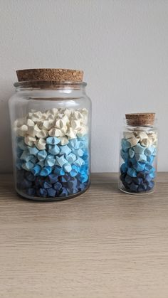 two jars filled with blue and white confetti on top of a wooden table