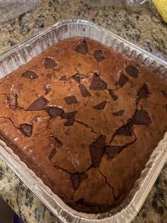 a cake in a pan with chocolate chips on it sitting on a counter top next to a banana