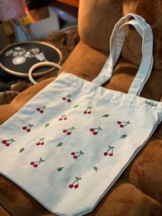 a white bag with cherries on it sitting on a chair