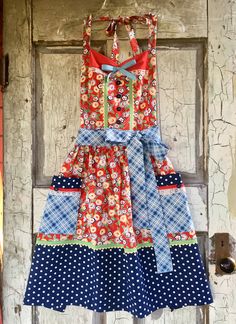 a dress hanging on a door with polka dots and flowery patterns in red, white, blue, and green