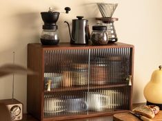 a wooden cabinet filled with lots of different types of coffee pots and pans on top of it