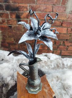 a metal flower vase sitting on top of a wooden table