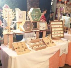 there are many jewelry on display at the table with people standing around it and looking at them