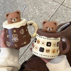 someone holding two mugs with teddy bears on them