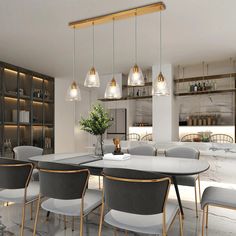 a dining room table with chairs and lights hanging from it's ceiling over the counter