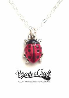 Hand Painted Red Ladybug Necklace.   The charm is made in the USA using lead-free Britannia pewter with a nickel compliant fine silver double plating. The charm is approximately 1/2 inches long and 3/8 inches wide. Kimberly hand painted the ladybugs using a nontoxic epoxy resin made with organic compounds. Red Themed Jewelry For Valentine's Day, Red Valentine's Day Themed Jewelry, Red Themed Necklace For Gift, Themed Red Necklace For Gifts, Cute Red Charm Necklaces For Gifts, Themed Red Necklace For Gift, Cute Red Charm Necklace For Gift, Red Novelty Jewelry For Gift, Red Novelty Jewelry As Gift