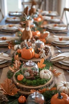 the table is set with pumpkins, pine cones and other decorations