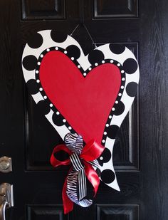 a heart shaped door hanger on a black door with red and white polka dots