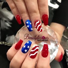 a woman's hand with red, white and blue nail polishes on it