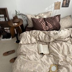 an unmade bed with a book on it