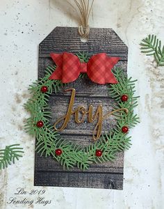 a christmas ornament hanging from the side of a wall with evergreen leaves and red bows