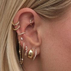 a close up of a person with ear piercings and gold jewelry on their ears