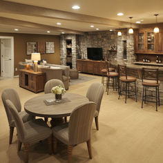 a living room filled with lots of furniture and a stone wall behind the bar area