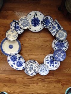 blue and white plates are arranged in a circle on the floor, with one being held by someone's hand