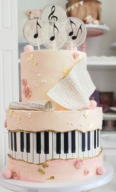 a pink cake decorated with musical notes and piano keys on top of a white table