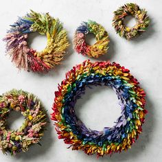 four pieces of art made out of different colored yarns on top of a white surface