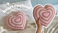 two crocheted heart cushions sitting on top of a bed