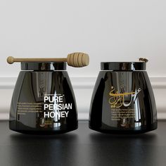 two black vases sitting on top of a table with a wooden stick sticking out of them