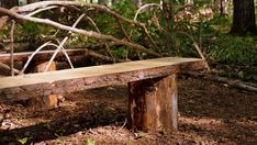 a bench made out of logs in the woods