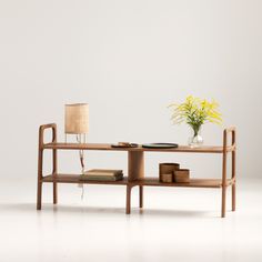 a wooden table with a lamp and some books on top of it next to a vase filled with flowers