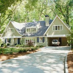 a car is parked in front of a house with trees and shrubs around it on the driveway