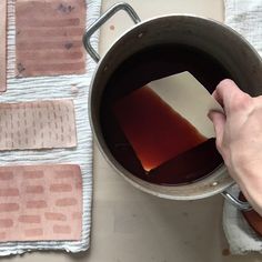 a person is holding a piece of paper in a pot full of liquid on a table