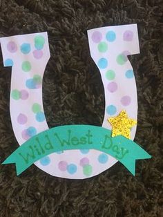 a paper cut out of the shape of a horseshoe with a green ribbon around it that says wild west day