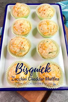 six muffins on a white plate with blue trim around the edges and title, biscuit zucchini cheddar muffins