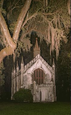 an old church with moss hanging from the trees